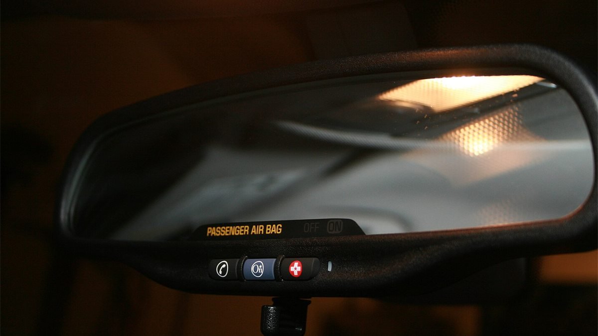 Retrovisor interno de um carro com três botões embaixo, um deles com o logotipo do OnStar