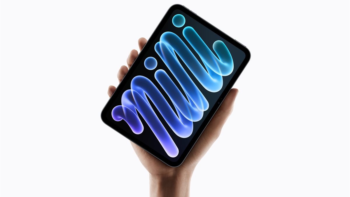 Mão segura um iPad mini inclinado contra fundo branco, com a palavra mini desenhada em traços azuis e roxos na tela