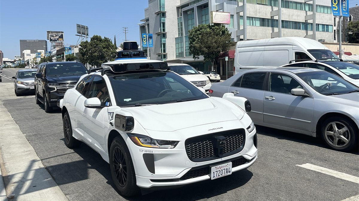 Jaguar I-Pace branco da Waymo, com sensores no teto, parado no trânsito de uma avenida de Los Angeles
